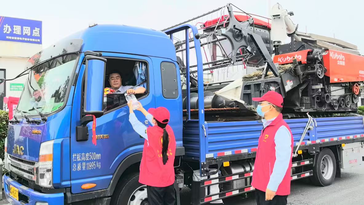 图二：构林收费站工作人员向跨区机收车辆发放矿泉水.jpg